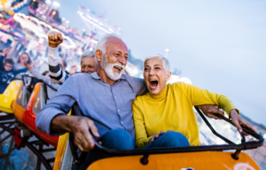Senior man and woman on a roller coaster ride having fun.